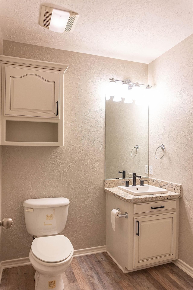 bathroom with hardwood / wood-style floors, vanity, a textured ceiling, and toilet