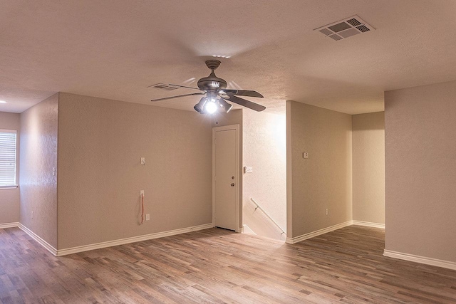 unfurnished room featuring a textured ceiling, light wood-type flooring, and ceiling fan