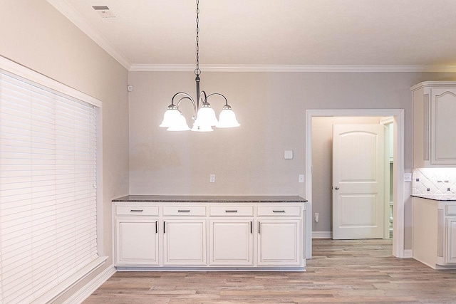 unfurnished dining area with light wood-type flooring, crown molding, and a chandelier