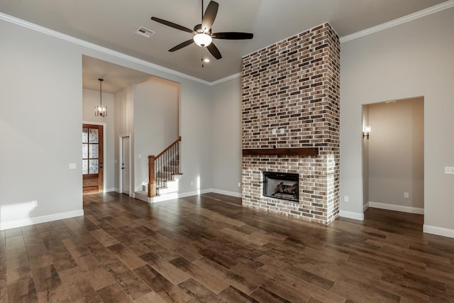 unfurnished living room with dark hardwood / wood-style floors, crown molding, ceiling fan with notable chandelier, and a brick fireplace