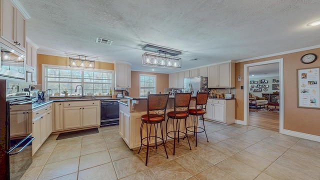 310 Junker Rd, Beaumont, TX 77707 - kitchen featuring black appliances, a sink, a kitchen island, a textured ceiling, and light tile patterned flooring