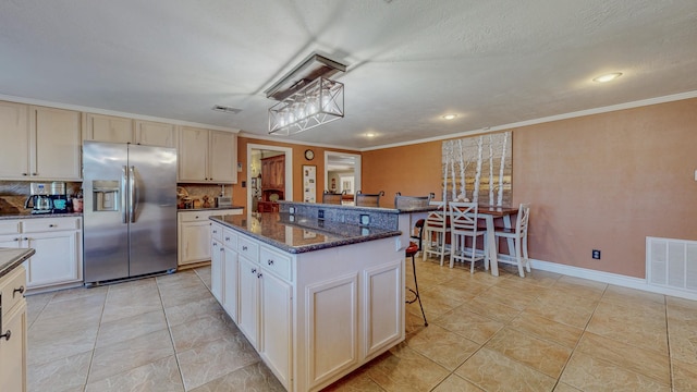 310 Junker Rd, Beaumont, TX 77707 - kitchen featuring stainless steel refrigerator with ice dispenser, a breakfast bar area, a kitchen island, light tile patterned floors, and ornamental molding
