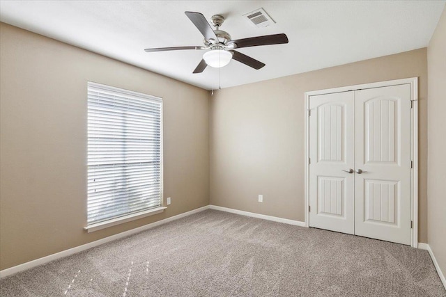 unfurnished bedroom with ceiling fan, a closet, light colored carpet, and multiple windows