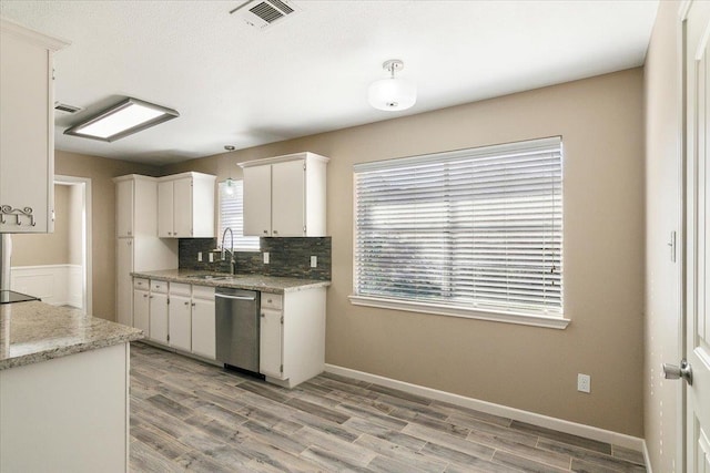 kitchen with dishwasher, sink, decorative backsplash, light stone counters, and white cabinetry