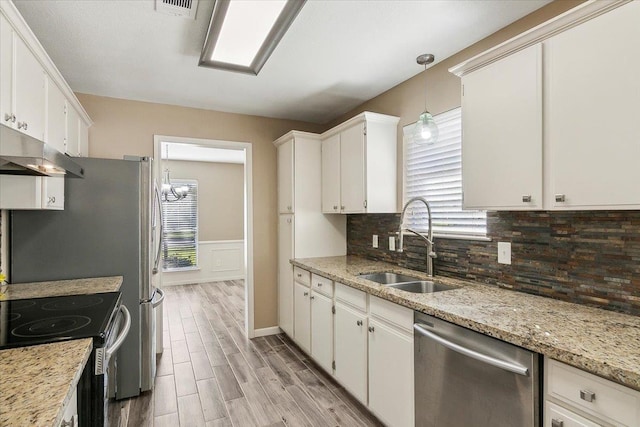 kitchen featuring light stone countertops, appliances with stainless steel finishes, sink, decorative light fixtures, and white cabinetry