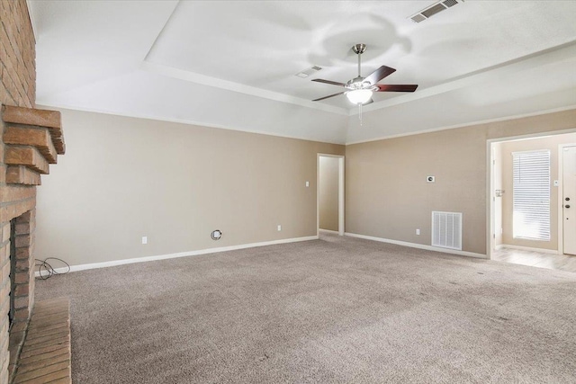 unfurnished living room featuring ceiling fan, a raised ceiling, carpet floors, and a fireplace