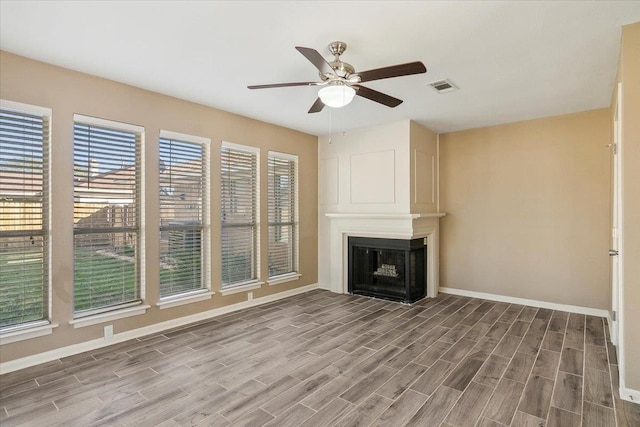 unfurnished living room featuring ceiling fan, a large fireplace, and hardwood / wood-style flooring