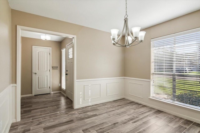 unfurnished dining area with hardwood / wood-style floors and an inviting chandelier