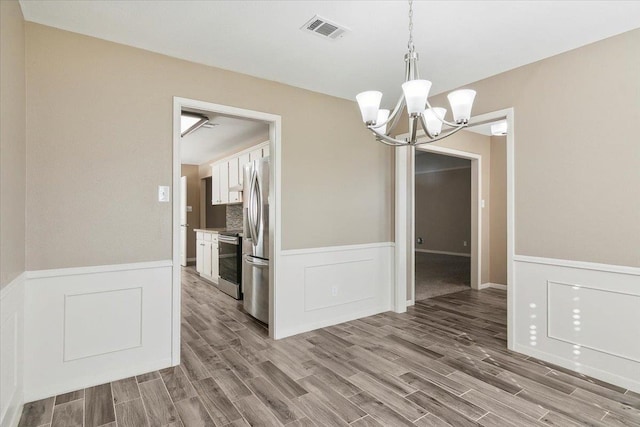 unfurnished dining area featuring hardwood / wood-style floors and a chandelier