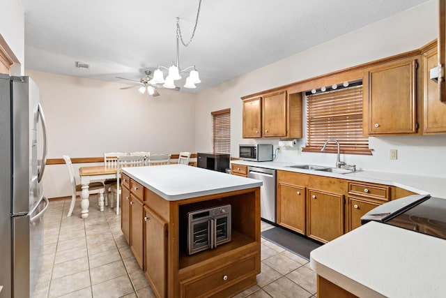 kitchen with a center island, sink, hanging light fixtures, stainless steel appliances, and light tile patterned flooring