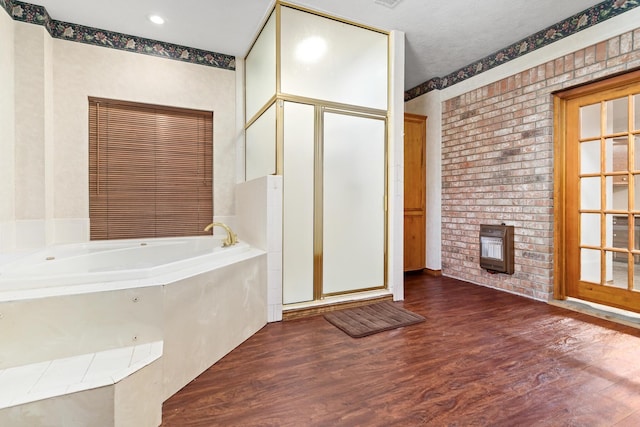 bathroom with hardwood / wood-style flooring, shower with separate bathtub, and brick wall