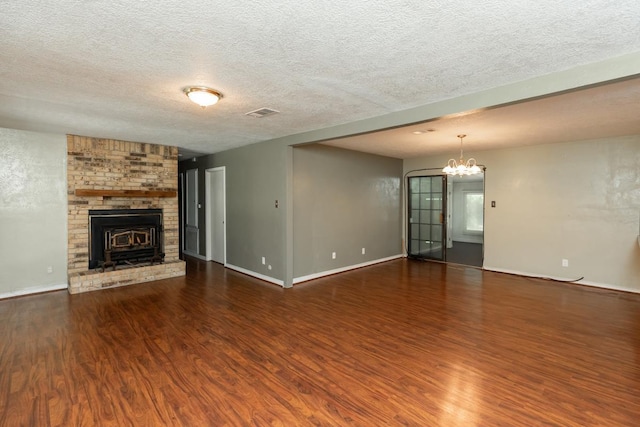 10754 Bonwell Loop, Kountze, TX 77625 - unfurnished living room featuring wood finished floors, a chandelier, a textured ceiling, and a fireplace