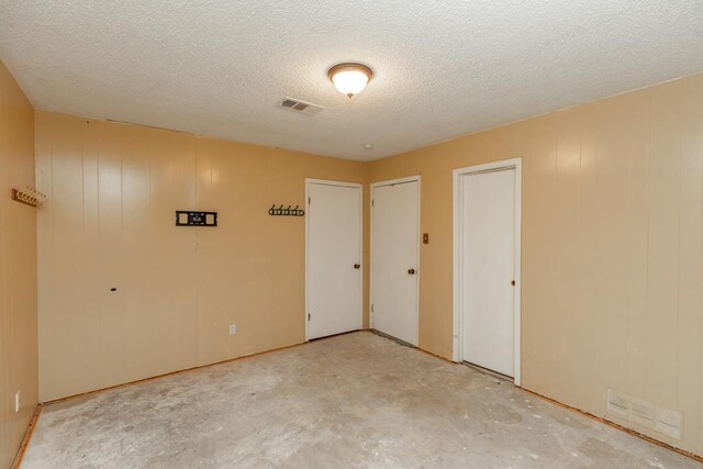 10754 Bonwell Loop, Kountze, TX 77625 - unfurnished bedroom with a textured ceiling, unfinished concrete flooring, and multiple closets