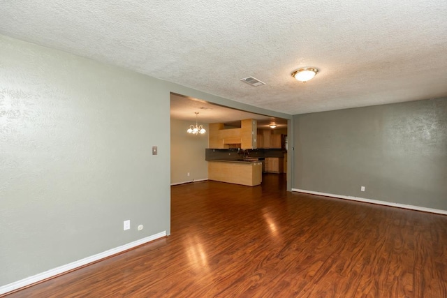 10754 Bonwell Loop, Kountze, TX 77625 - unfurnished living room with dark wood-style floors, a chandelier, and a textured ceiling