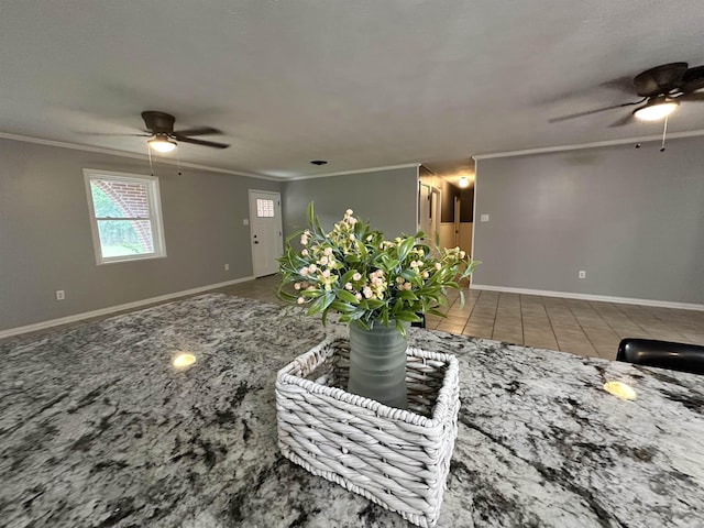 unfurnished living room featuring crown molding, a ceiling fan, and baseboards
