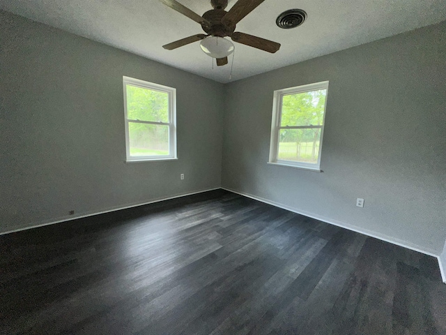 unfurnished room with dark wood-type flooring, ceiling fan, and a healthy amount of sunlight