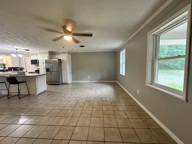 unfurnished living room with ornamental molding, a sink, ceiling fan, and light tile patterned flooring