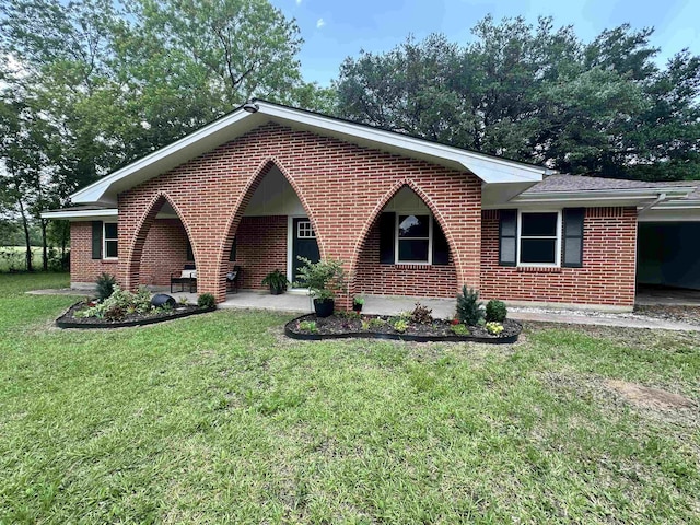 ranch-style home featuring brick siding, a front lawn, and a carport