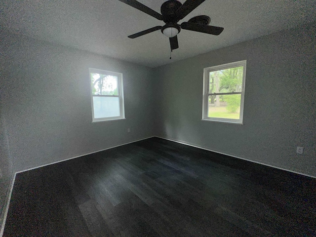 spare room with baseboards, a ceiling fan, and dark wood finished floors