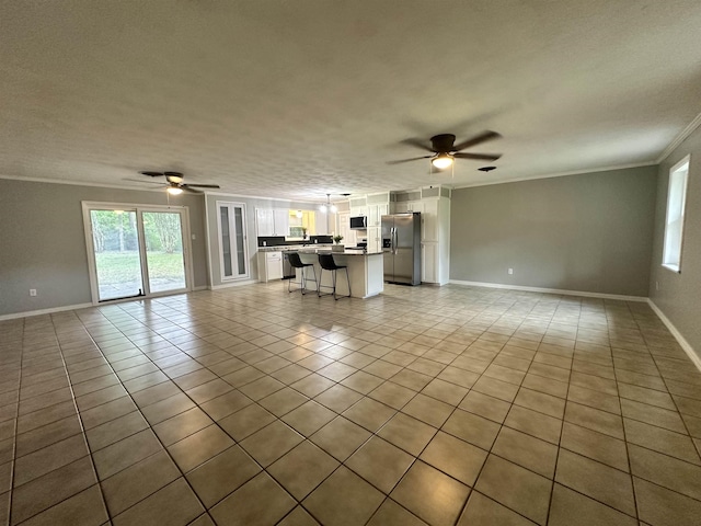 unfurnished living room featuring ornamental molding, ceiling fan, and light tile patterned flooring