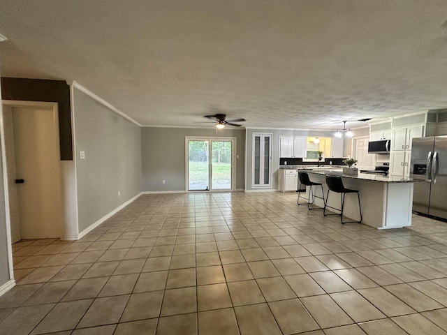 unfurnished living room with crown molding, ceiling fan, light tile patterned flooring, and a wealth of natural light