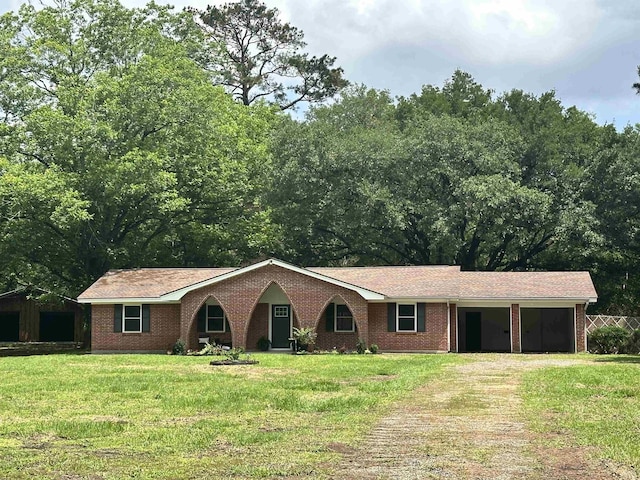single story home featuring brick siding, driveway, and a front yard