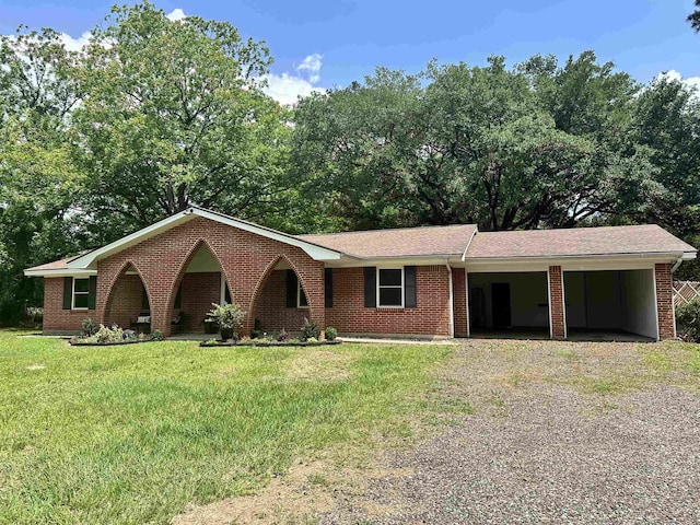 ranch-style house featuring brick siding, driveway, a front lawn, and an attached carport