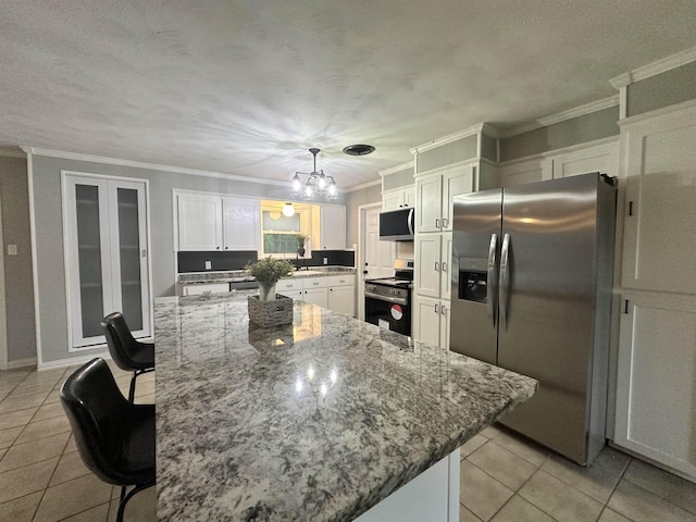 kitchen with a kitchen bar, crown molding, appliances with stainless steel finishes, light tile patterned floors, and white cabinetry