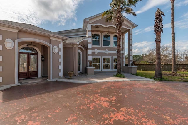 view of front of house with french doors, fence, and stucco siding