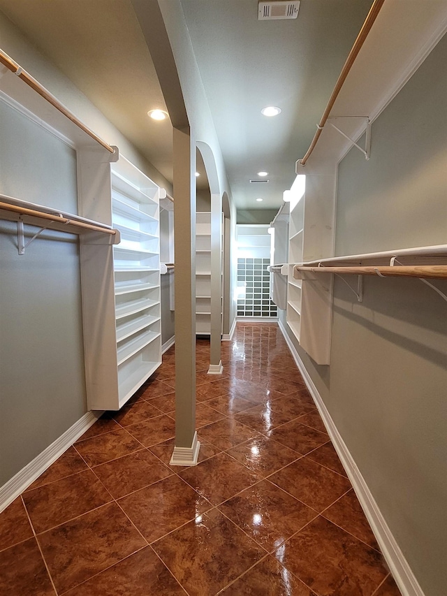 walk in closet featuring arched walkways, visible vents, and dark tile patterned flooring