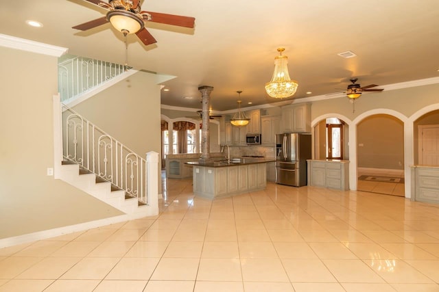 kitchen featuring dark countertops, arched walkways, appliances with stainless steel finishes, light tile patterned flooring, and crown molding