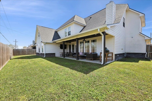 back of property with a patio, an outdoor living space, a fenced backyard, a chimney, and a lawn