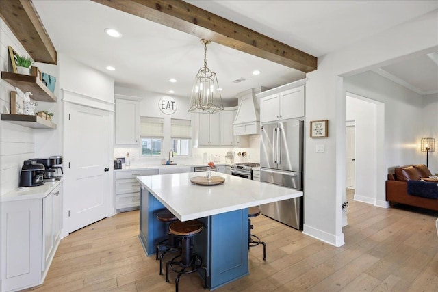 kitchen with premium range hood, beamed ceiling, light wood-type flooring, a kitchen bar, and appliances with stainless steel finishes