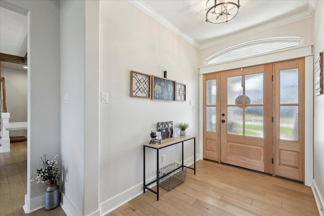 entryway with light wood-type flooring, baseboards, a notable chandelier, and ornamental molding