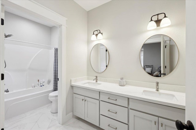 bathroom featuring double vanity, marble finish floor, toilet, and a sink