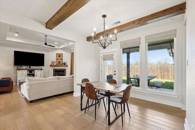 dining room featuring visible vents, baseboards, beam ceiling, light wood-style flooring, and a fireplace