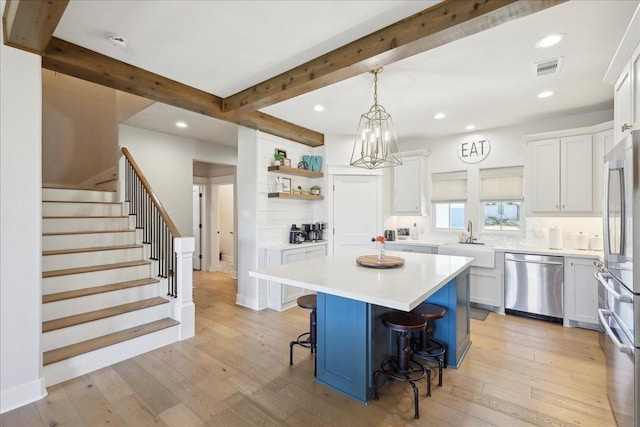 kitchen featuring light wood-style flooring, a kitchen breakfast bar, stainless steel appliances, and a sink