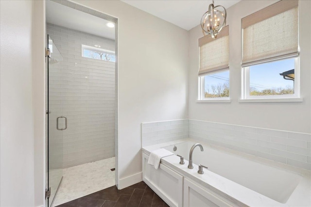 full bath with tile patterned flooring, a shower stall, baseboards, a chandelier, and a garden tub