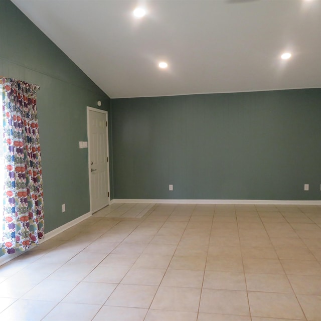 empty room featuring baseboards, vaulted ceiling, and light tile patterned flooring