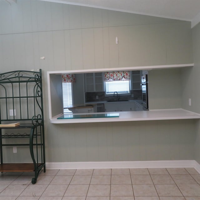 kitchen with lofted ceiling, tile patterned flooring, a sink, stainless steel oven, and crown molding