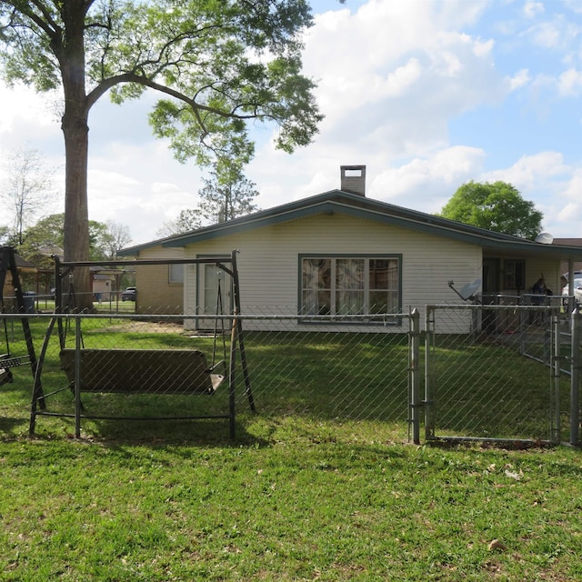 rear view of house featuring a yard, a gate, fence, and a chimney