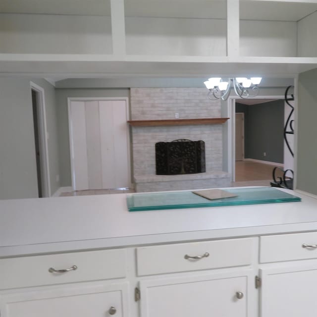 kitchen with light countertops, a brick fireplace, open shelves, and white cabinetry