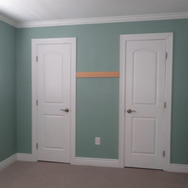 unfurnished bedroom with carpet floors, ornamental molding, and baseboards