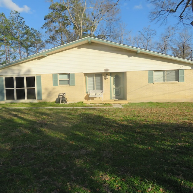 rear view of house with brick siding and a yard