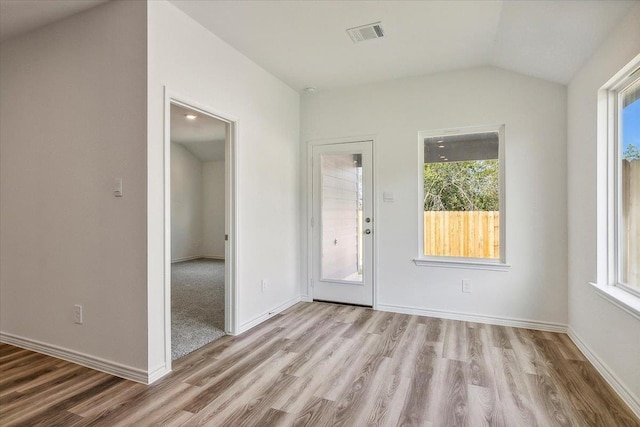 spare room featuring light wood-type flooring and vaulted ceiling