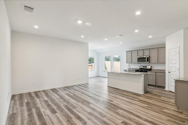 kitchen featuring a kitchen island with sink, sink, gray cabinets, light hardwood / wood-style floors, and stainless steel appliances