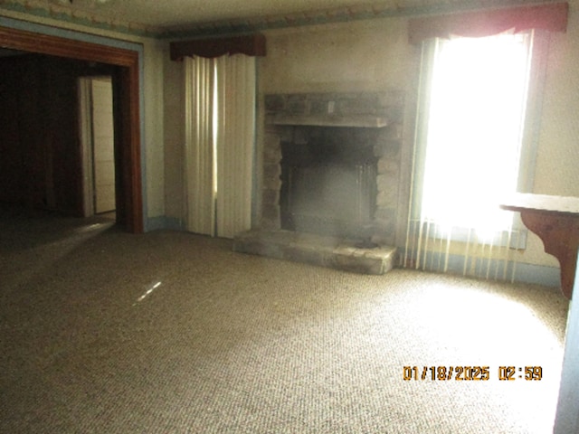 unfurnished living room with a stone fireplace and carpet flooring