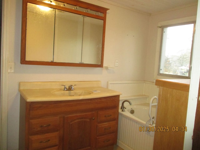 bathroom with vanity, crown molding, and a tub