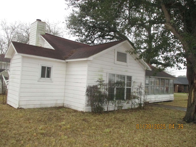 view of home's exterior featuring a sunroom and a lawn