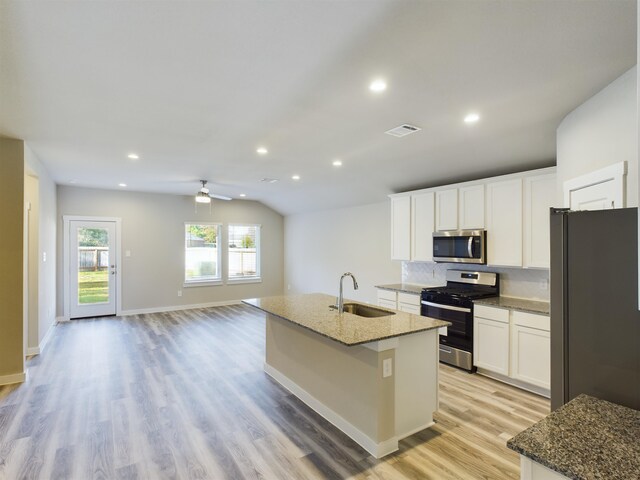 kitchen with sink, an island with sink, appliances with stainless steel finishes, stone countertops, and white cabinetry